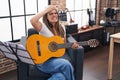 Young beautiful woman playing classic guitar at music studio stressed and frustrated with hand on head, surprised and angry face Royalty Free Stock Photo