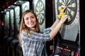 Young beautiful woman playing darts in a club