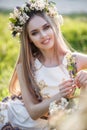 Young beautiful woman with a pleasant smile in alone in a wreath of fresh flowers walks in a spring flowering park Royalty Free Stock Photo