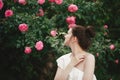 Young beautiful woman portrait close up with perfect skin posing with pink roses flowers in a garden Royalty Free Stock Photo