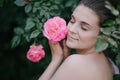 Young beautiful woman portrait close up with perfect skin posing with pink roses flowers in a garden Royalty Free Stock Photo