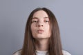 Young beautiful woman portrait with dark hair wearing white sweater show kiss show ideal lips send air kisses .Studio shot on gray Royalty Free Stock Photo