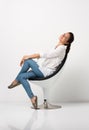 Young beautiful woman posing in a chair in front of a white wall
