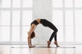 Young beautiful woman practicing yoga near floor window in yoga studio. Girl doing exercises at class. Royalty Free Stock Photo