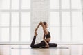 Young beautiful woman practicing yoga near floor window in yoga studio. Girl doing exercises at class. Royalty Free Stock Photo