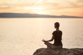 Young woman practicing yoga near the sea at sunset. Harmony, meditation and travel concept. Healthy lifestyle Royalty Free Stock Photo