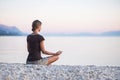 Young woman practicing yoga near the sea at sunset. Harmony, meditation and travel concept. Healthy lifestyle Royalty Free Stock Photo