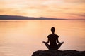 Young woman practicing yoga near the sea at sunset. Harmony, meditation and travel concept. Healthy lifestyle