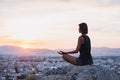 Young woman practicing yoga outdoors at sunset with a big city at the background. Harmony, meditation and healthy lifestyle concep Royalty Free Stock Photo