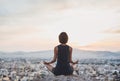 Young woman practicing yoga outdoors at sunset with a big city at the background. Harmony, meditation and healthy lifestyle concep Royalty Free Stock Photo