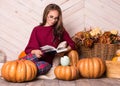 Young beautiful woman with pumpkins. Beautiful girl with glasses reads a book. Young pretty woman reading a book. Royalty Free Stock Photo