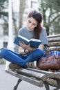 Young beautiful woman reading blue book in the street.