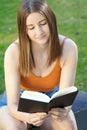 Young beautiful woman reading a book on a sunny day in park Royalty Free Stock Photo