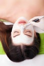 Young beautiful woman receiving clay facial mask in spa beauty salon. Skin care, Beauty treatments. Royalty Free Stock Photo