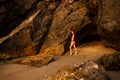 Young beautiful woman in red bikini swimsuit posing standing on the sand, next to the rocks on the beach in Goa India Royalty Free Stock Photo