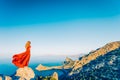 Young beautiful woman in red dress looking to mountains sea Royalty Free Stock Photo