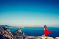 Young beautiful woman in red dress looking to mountains sea Royalty Free Stock Photo
