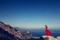 Young beautiful woman in red dress looking to mountains sea Royalty Free Stock Photo