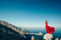 Young beautiful woman in red dress looking to mountains sea Royalty Free Stock Photo