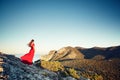 Young beautiful woman in red dress looking to mountains sea Royalty Free Stock Photo