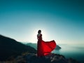 Young beautiful woman in red dress looking to mountains sea Royalty Free Stock Photo