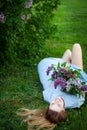 Young beautiful woman with red hair lies on the grass under the lilac tree and enjoys her life Royalty Free Stock Photo