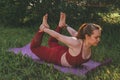 Young beautiful woman in red leggings and a top practicing yoga in a city park