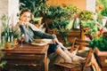 Young beautiful woman relaxing on cozy balcony, reading a book