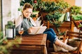 Young beautiful woman relaxing on cozy balcony, reading a book