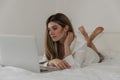 Young beautiful woman relaxing and lies on the bed using laptop computer in the bedroom. Online chat. Working from home. Royalty Free Stock Photo