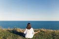 Young beautiful woman relaxing and practicing yoga on beach, sitting in grass, meditating and listening to sea waves. Hipster girl Royalty Free Stock Photo