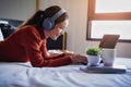 Young beautiful woman relaxing with use headphones listening to music and laptop on bed in the holiday Royalty Free Stock Photo