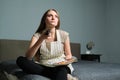 Young beautiful woman with remote control, serious female sitting at home and watching tv Royalty Free Stock Photo