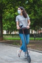 Young Beautiful woman riding an electric scooter to work with mask, modern girl, new generaron, electric transport, ecology Royalty Free Stock Photo