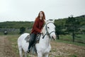 Young beautiful woman riding a horse on a white horse in the mountains, nature