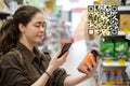 Young beautiful woman scans a QR code product in the supermarket. The concept of modern technology Royalty Free Stock Photo