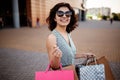 Young beautiful woman shopaholic walks out the shopping center with a pack of bags with purchases. Pink shopper in the hand of an