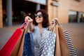 Young beautiful woman shopaholic walks out the shopping center with a pack of bags with purchases. Pink shopper in the hand of an