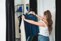 Young beautiful woman shopping, going to fitting room in fashion mall, making decision on what to buy, holding two hangers with Royalty Free Stock Photo