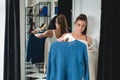 Young beautiful woman shopping, going to fitting room in fashion mall, making decision on what to buy, holding two hangers with Royalty Free Stock Photo