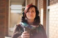 Young beautiful woman with short red hair and headphones with coffee to go cup