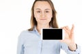 Young beautiful woman shows in camera the blank black screen of smart phone on white background Royalty Free Stock Photo