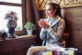 Young beautiful woman sits in cafe, looks out of window and drinks hot tea from cup. Royalty Free Stock Photo