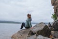 Young beautiful woman sits on the rocks on the seashore