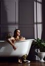 Young beautiful woman sitting in bathroom near expensive bathtub bath looking at the corner on dark Royalty Free Stock Photo