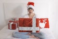 young beautiful woman sitting on bed and holding a christmas present. Home, indoors. Xmas concept Royalty Free Stock Photo