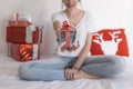 young beautiful woman sitting on bed and holding a christmas present. Home, indoors. Xmas concept Royalty Free Stock Photo