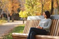 Young beautiful woman sitting on bench in autumn park Royalty Free Stock Photo