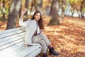 A young beautiful woman is sitting on a bench in an autumn park Royalty Free Stock Photo