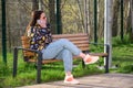 Young beautiful woman sitting on a bench in the city park and speaking on the phone Royalty Free Stock Photo
